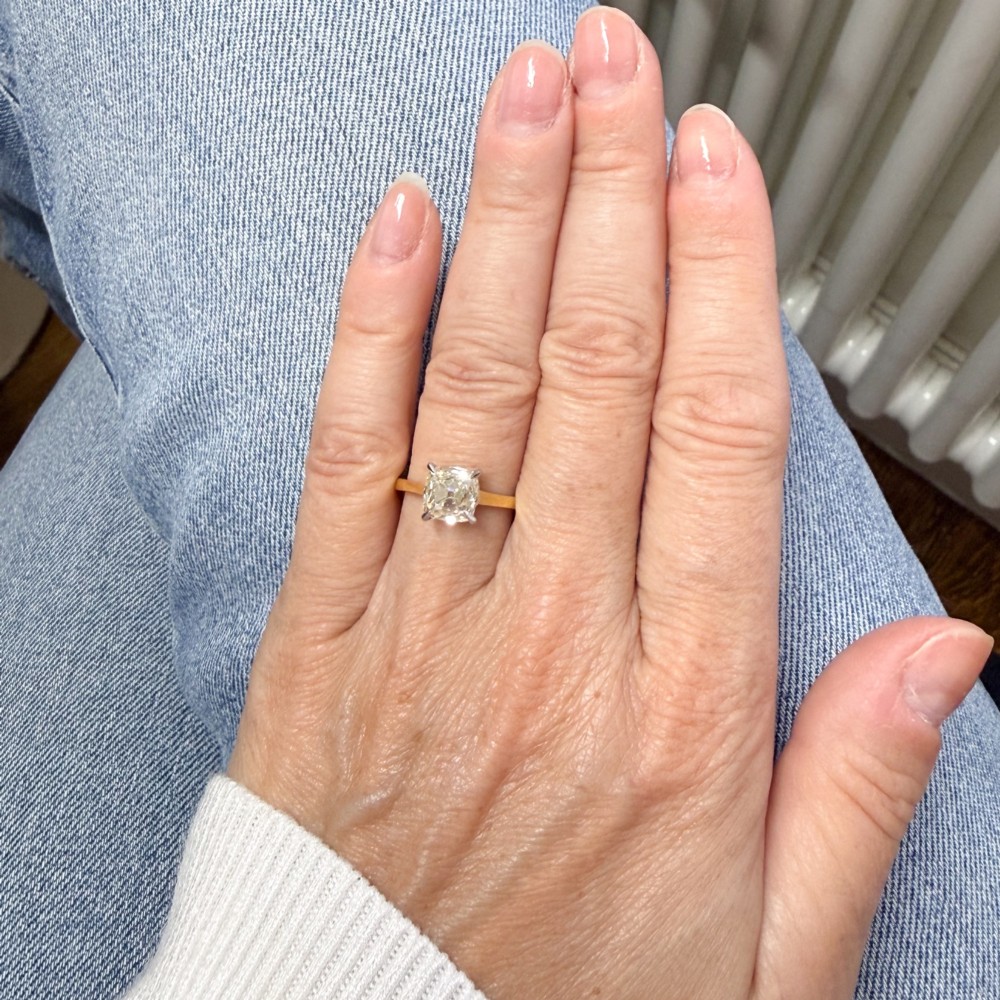 A vintage solitaire engagement ring featuring an old cut cushion diamond held in platinum claws on a tapered yellow gold band. View VII