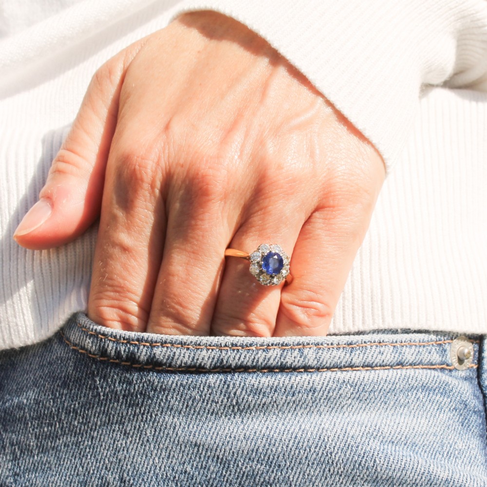 A yellow gold vintage ring featuring a central round blue sapphire encircled by a halo of brilliant-cut diamonds. View II