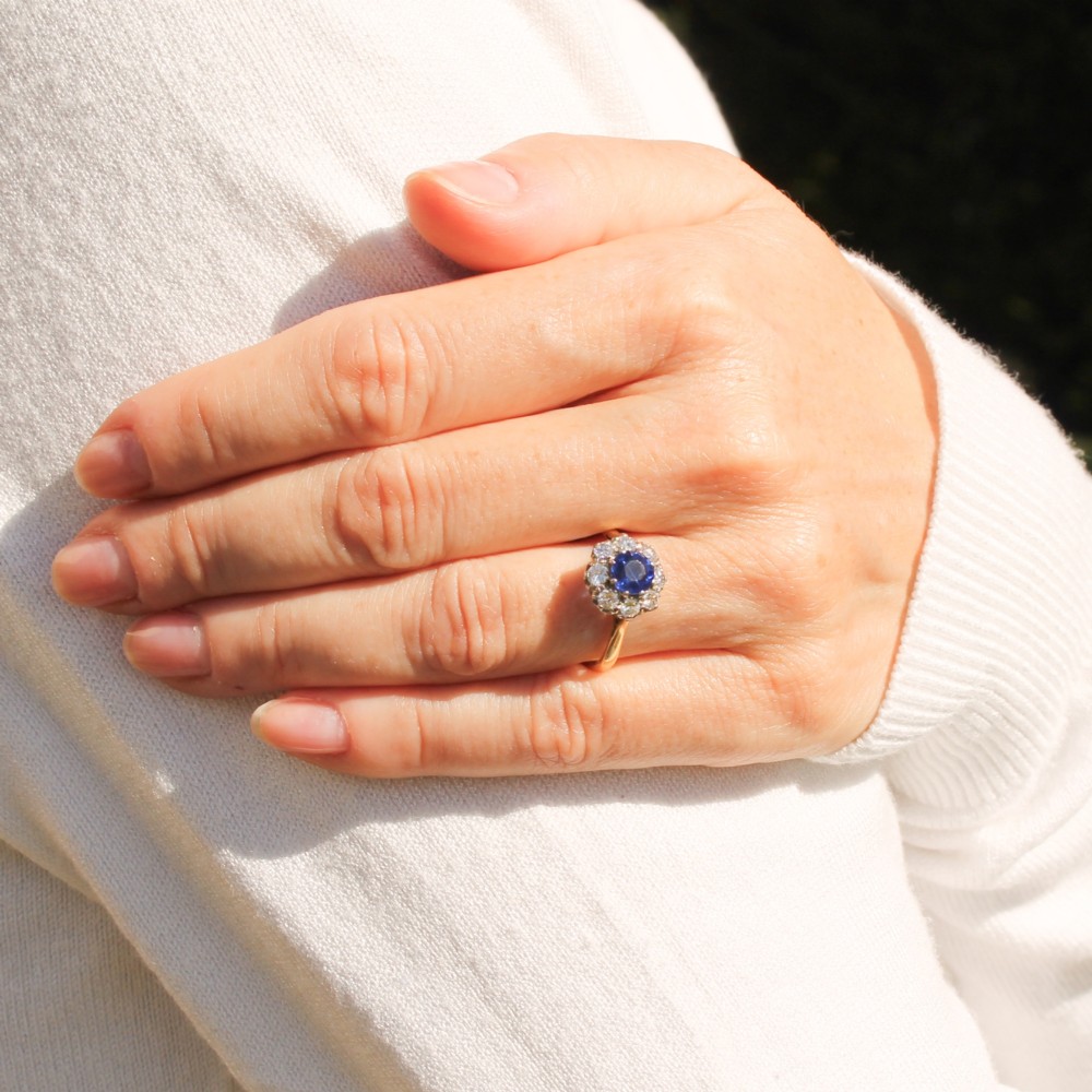 A yellow gold vintage ring featuring a central round blue sapphire encircled by a halo of brilliant-cut diamonds. View VII