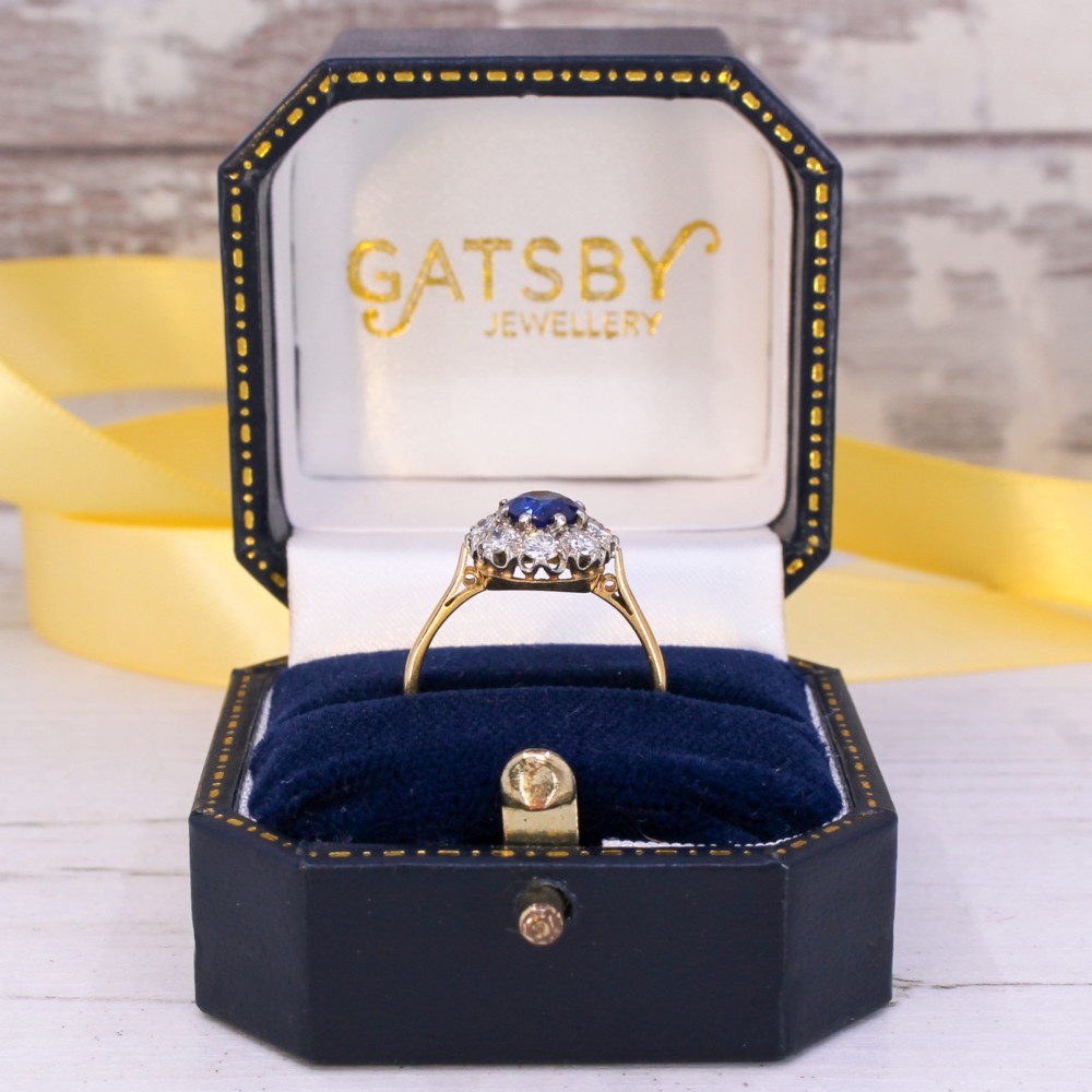 A yellow gold vintage ring featuring a central round blue sapphire encircled by a halo of brilliant-cut diamonds. View IX