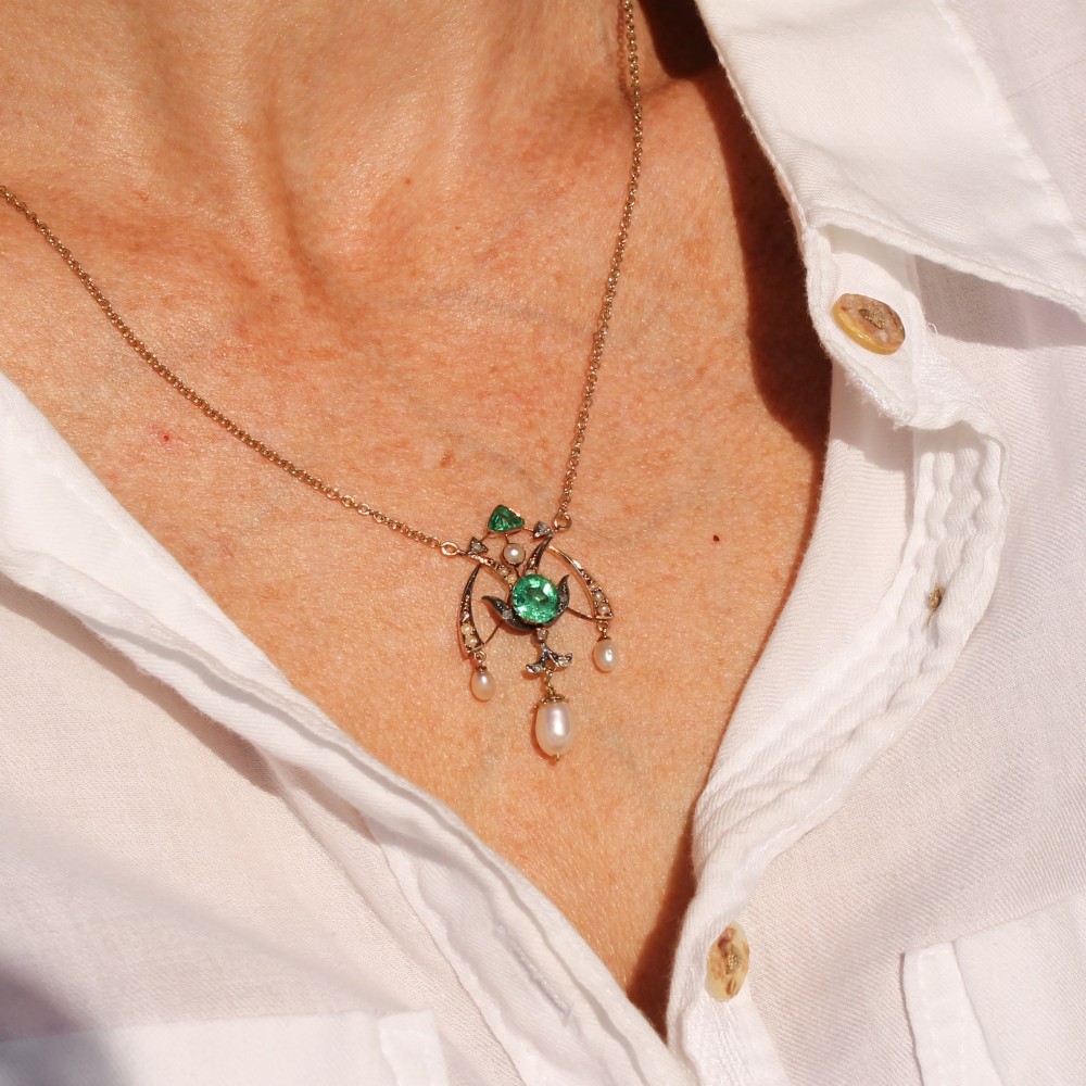 An Art Nouveau openwork gold pendant featuring a central round green emerald, diamond accents, and hanging natural pearl drops. View III