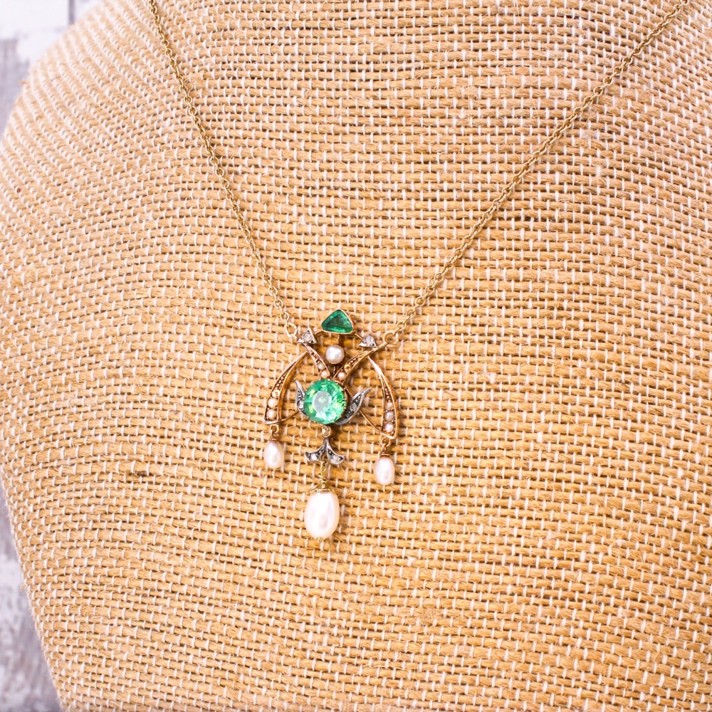 An Art Nouveau openwork gold pendant featuring a central round green emerald, diamond accents, and hanging natural pearl drops. View IV