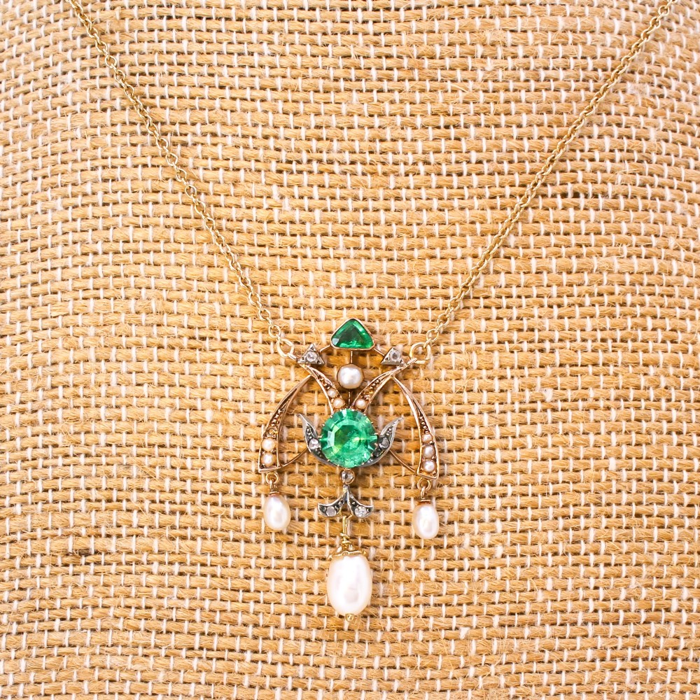 An Art Nouveau openwork gold pendant featuring a central round green emerald, diamond accents, and hanging natural pearl drops. View V