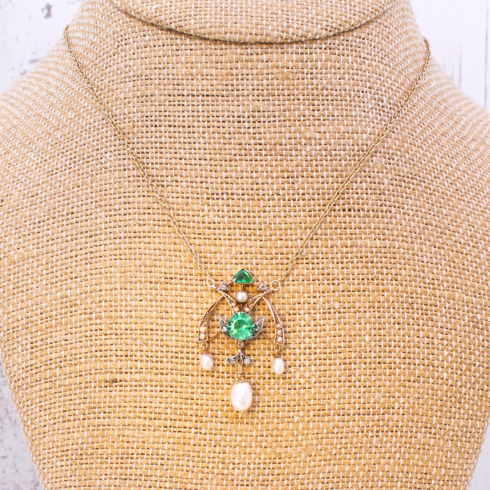 An Art Nouveau openwork gold pendant featuring a central round green emerald, diamond accents, and hanging natural pearl drops. View VI