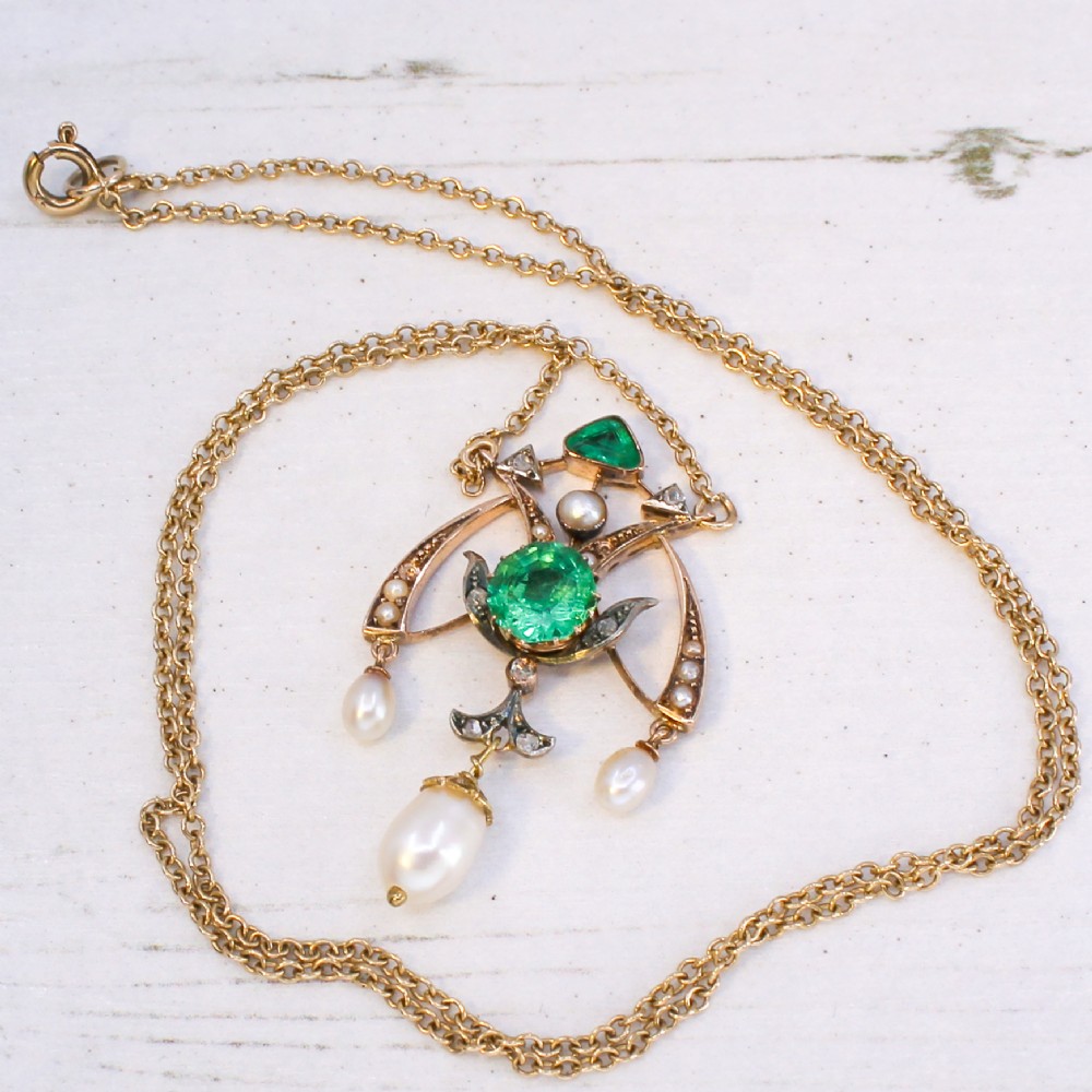 An Art Nouveau openwork gold pendant featuring a central round green emerald, diamond accents, and hanging natural pearl drops. View VII