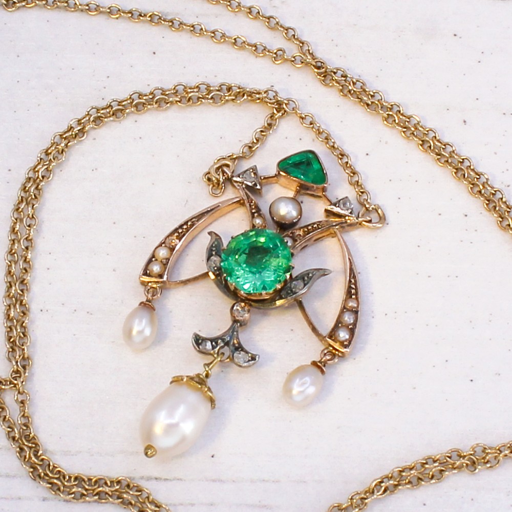 An Art Nouveau openwork gold pendant featuring a central round green emerald, diamond accents, and hanging natural pearl drops. View VIII