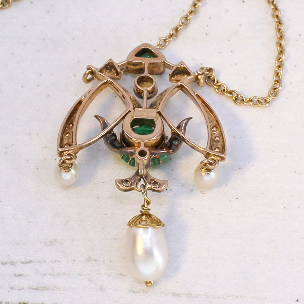 An Art Nouveau openwork gold pendant featuring a central round green emerald, diamond accents, and hanging natural pearl drops. View IX