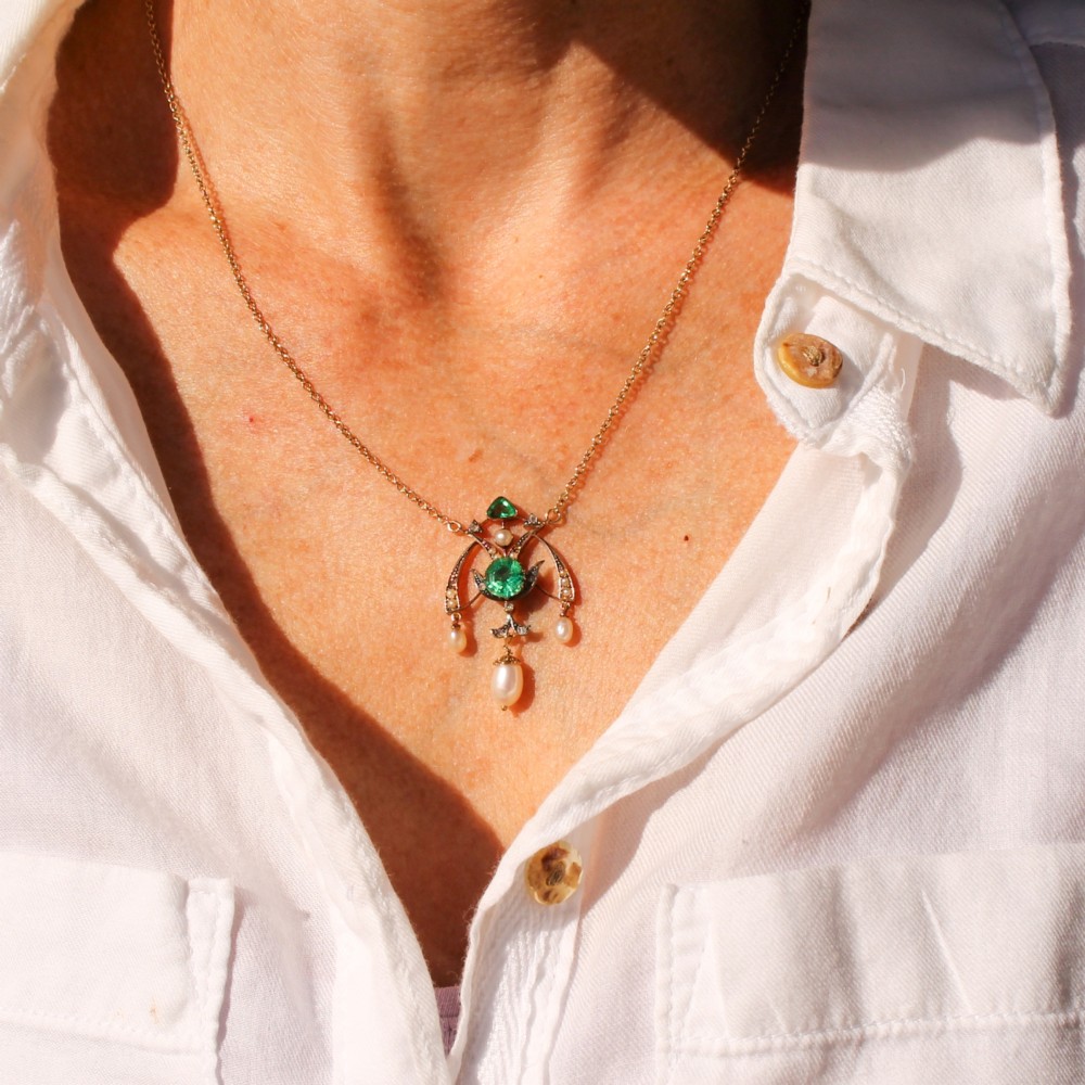 An Art Nouveau openwork gold pendant featuring a central round green emerald, diamond accents, and hanging natural pearl drops. View XI