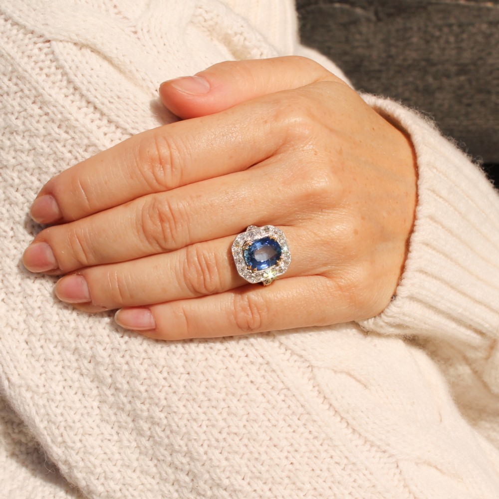 An antique Edwardian cluster ring featuring a central cushion-cut blue Ceylon sapphire surrounded by a halo of diamonds set in platinum and yellow gold. View II