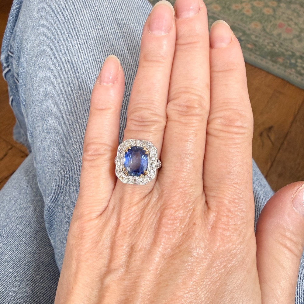 An antique Edwardian cluster ring featuring a central cushion-cut blue Ceylon sapphire surrounded by a halo of diamonds set in platinum and yellow gold. View VII
