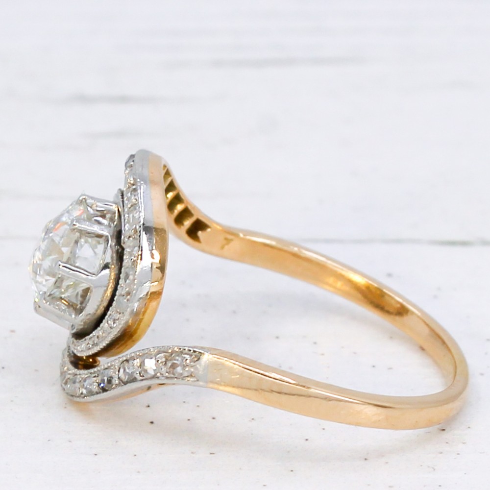 An antique Edwardian diamond ring featuring a central old cut diamond wrapped in a platinum-faced swirl setting studded with small accent diamonds on a yellow gold band. View IV