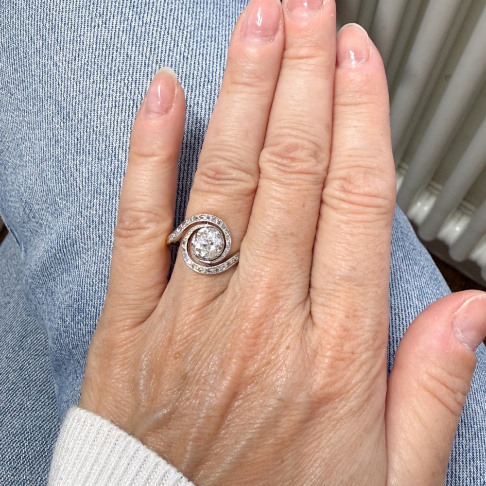 An antique Edwardian diamond ring featuring a central old cut diamond wrapped in a platinum-faced swirl setting studded with small accent diamonds on a yellow gold band. View IX