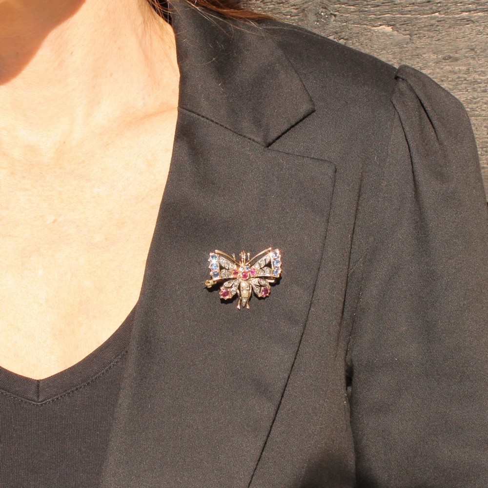 A Victorian butterfly brooch set with rubies, sapphires, diamonds, and natural pearls in silver and gold. View II