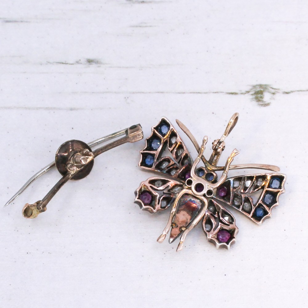 A Victorian butterfly brooch set with rubies, sapphires, diamonds, and natural pearls in silver and gold. View VI