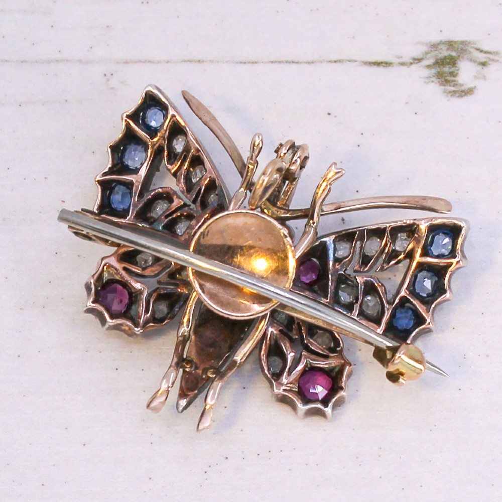 A Victorian butterfly brooch set with rubies, sapphires, diamonds, and natural pearls in silver and gold. View VII
