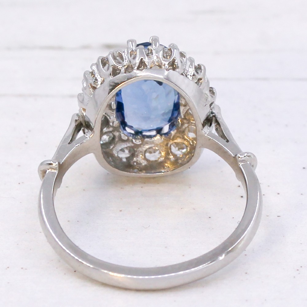 An oval blue Ceylon sapphire encircled by a halo of brilliant diamonds set on a silver metal band. View V