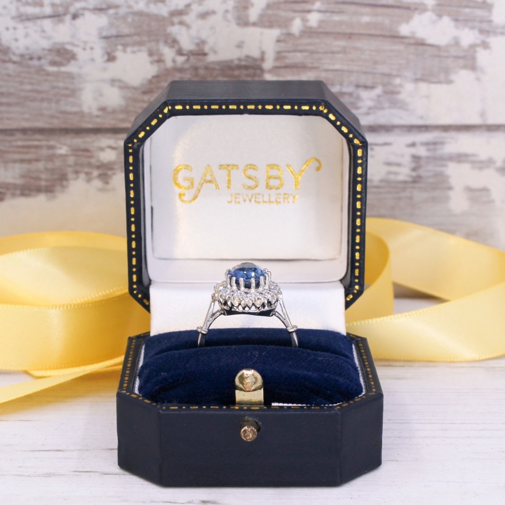 An oval blue Ceylon sapphire encircled by a halo of brilliant diamonds set on a silver metal band. View VIII