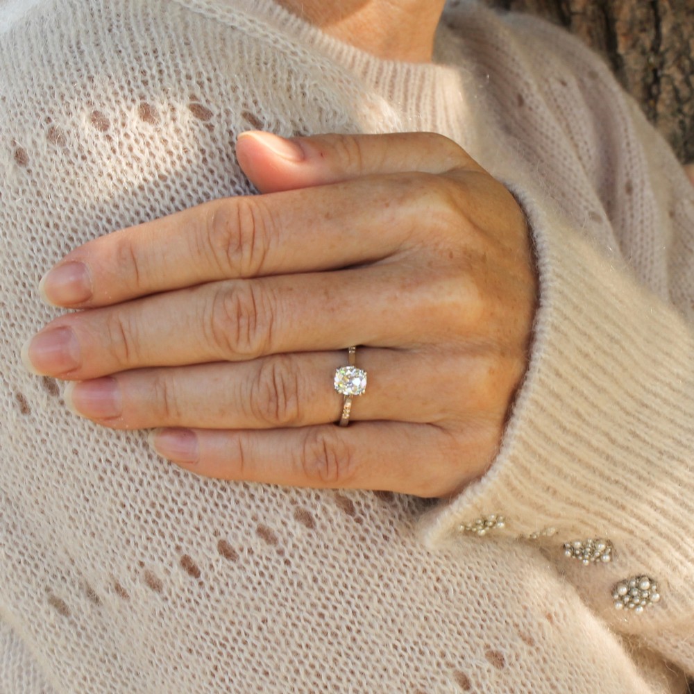 A platinum vintage ring featuring a central cushion-shaped old cut diamond held in a multi-claw setting with detailed shoulders. View VI