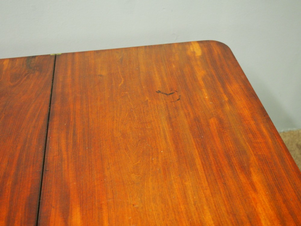 A 19th-century William IV mahogany fold-over table featuring a rounded rectangular top, a thick turned central pedestal, a concave quadform base, and brass castors. View IX