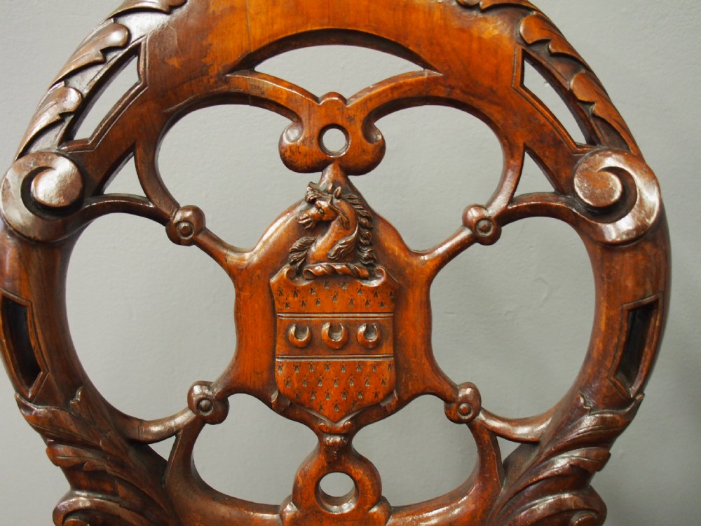 Set of three Victorian mahogany hall chairs featuring openwork carved backs inset with central heraldic crests and shaped front legs. View VII
