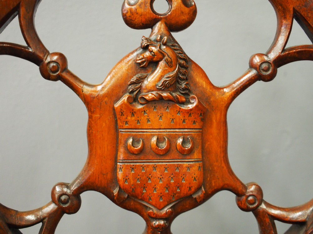 Set of three Victorian mahogany hall chairs featuring openwork carved backs inset with central heraldic crests and shaped front legs. View X