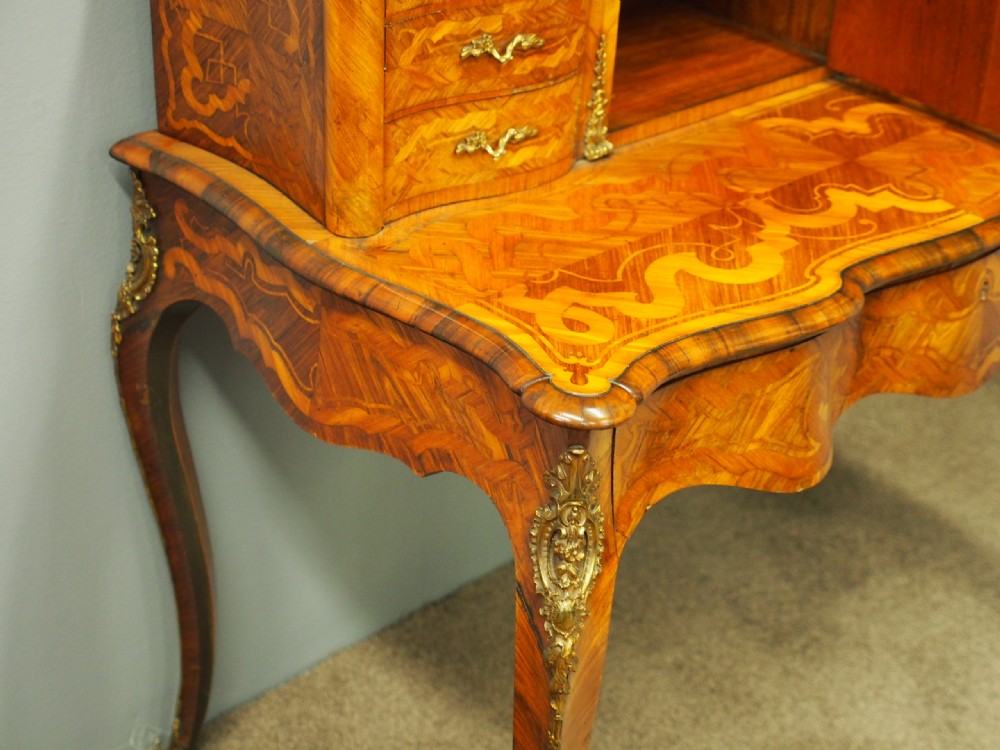 A French Rococo Revival ladies writing desk featuring intricate wood marquetry, gilt-bronze mounts, cabriole legs, and a central cabinet door set with a hand-painted porcelain plaque. View IV