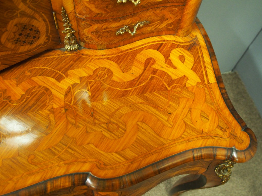 A French Rococo Revival ladies writing desk featuring intricate wood marquetry, gilt-bronze mounts, cabriole legs, and a central cabinet door set with a hand-painted porcelain plaque. View X
