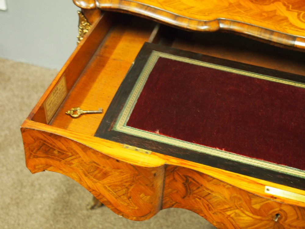A French Rococo Revival ladies writing desk featuring intricate wood marquetry, gilt-bronze mounts, cabriole legs, and a central cabinet door set with a hand-painted porcelain plaque. View XIII
