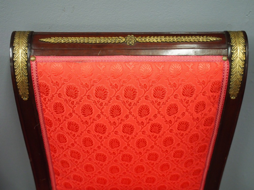 A pair of 19th-century Empire Revival side chairs featuring dark mahogany frames, winged lion gilt monopodia front legs, and red patterned silk upholstery. View VI