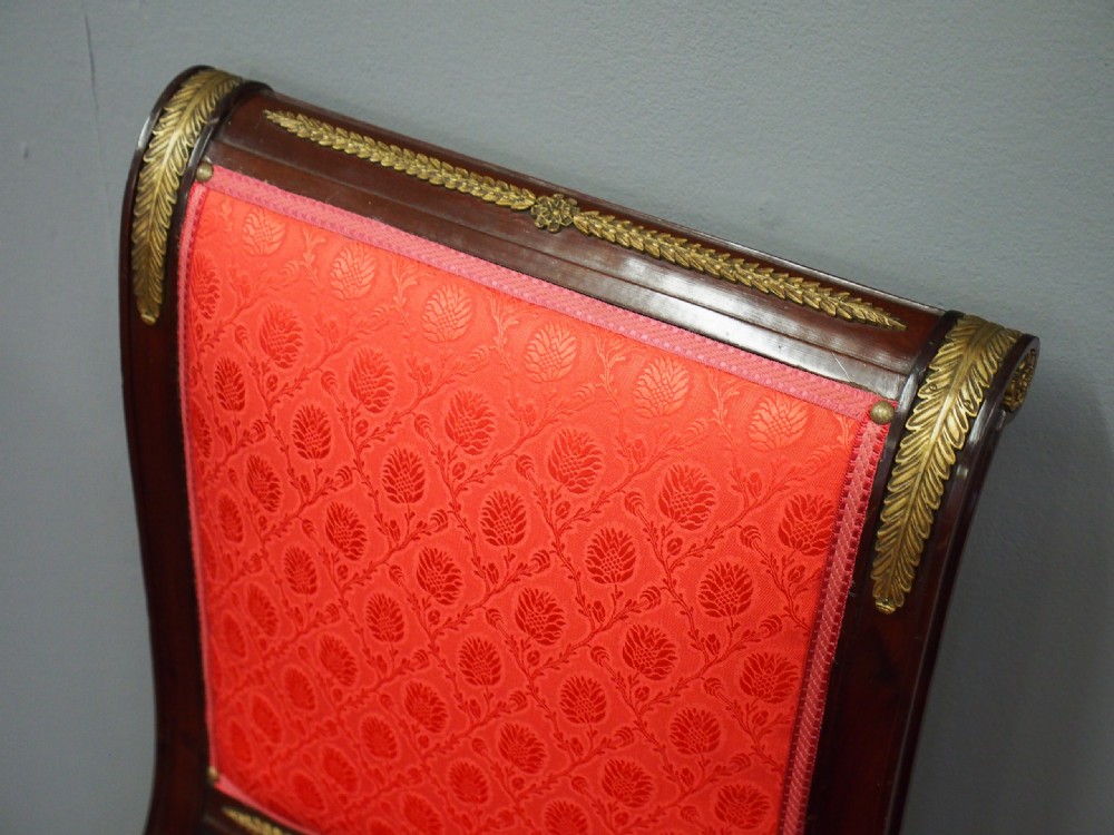 A pair of 19th-century Empire Revival side chairs featuring dark mahogany frames, winged lion gilt monopodia front legs, and red patterned silk upholstery. View VII