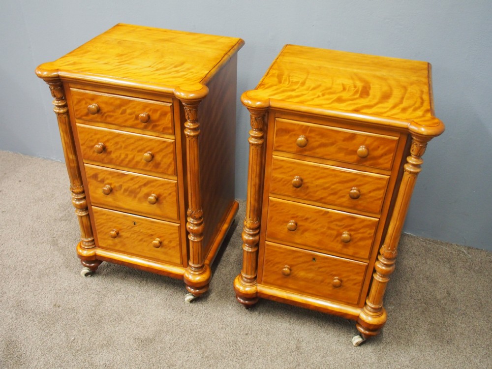 A pair of Victorian satin birch pedestal chests featuring four stacked drawers, turned corner columns, wooden knob handles, and castors. View VII
