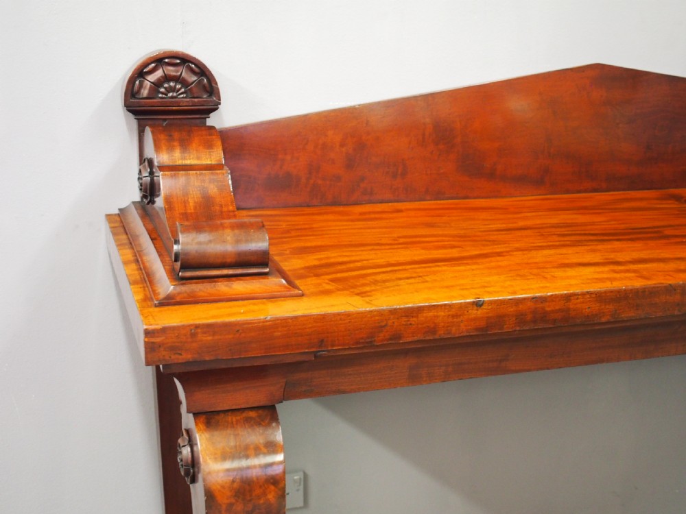 A Scottish Regency mahogany serving table featuring a raised shaped gallery back with carved round scroll details and curved front legs. View V