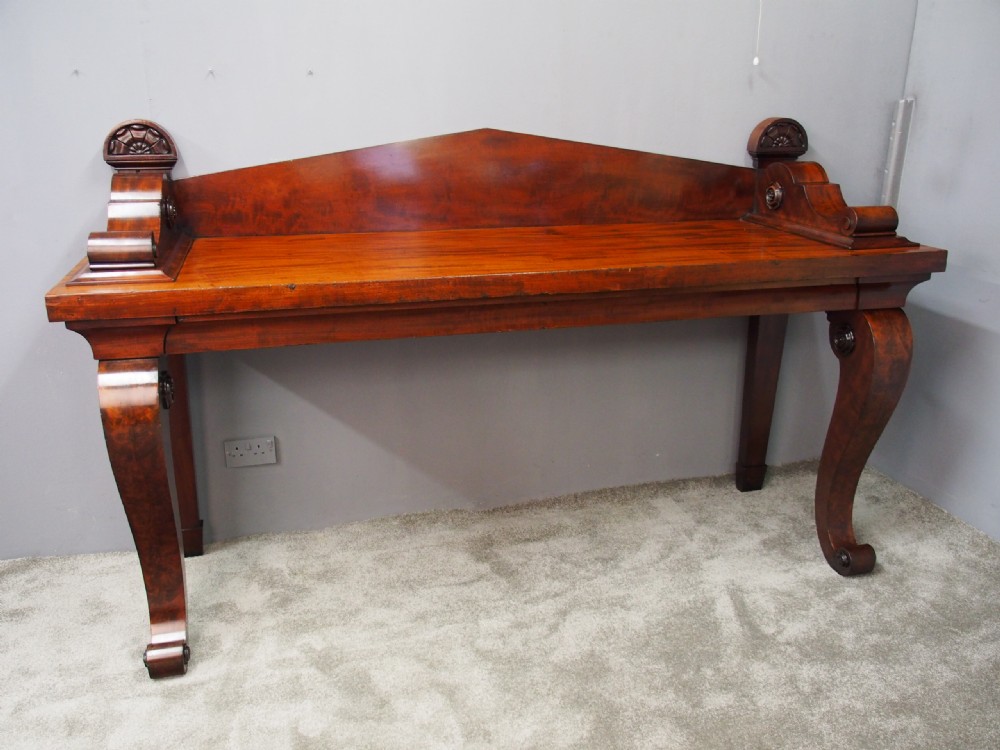 A Scottish Regency mahogany serving table featuring a raised shaped gallery back with carved round scroll details and curved front legs. View XII