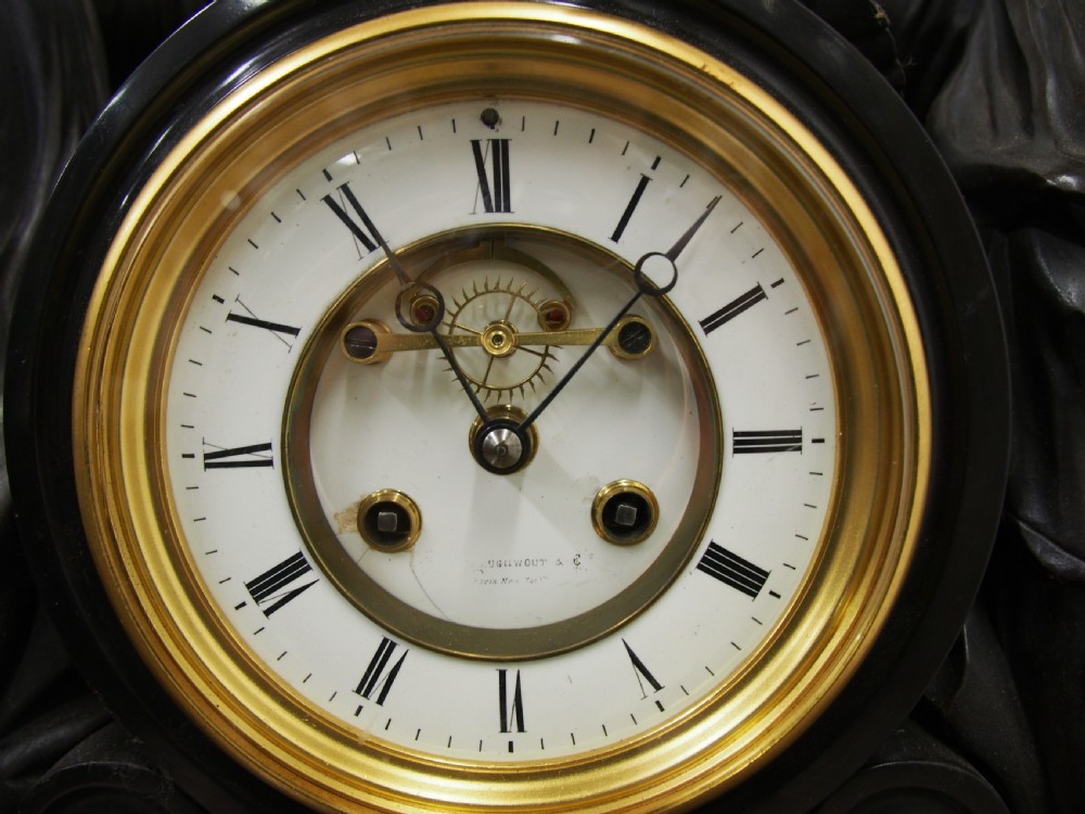 A three-piece French antique clock garniture featuring a central mantel clock flanked by classical female figures and two standalone bronze male sculptures on dark marble bases. View III