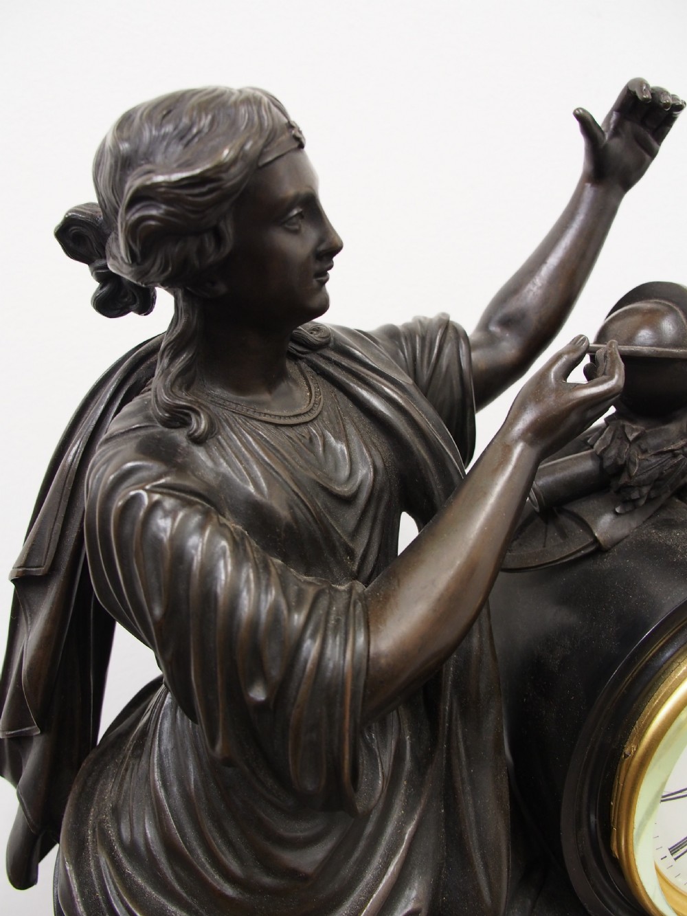 A three-piece French antique clock garniture featuring a central mantel clock flanked by classical female figures and two standalone bronze male sculptures on dark marble bases. View V