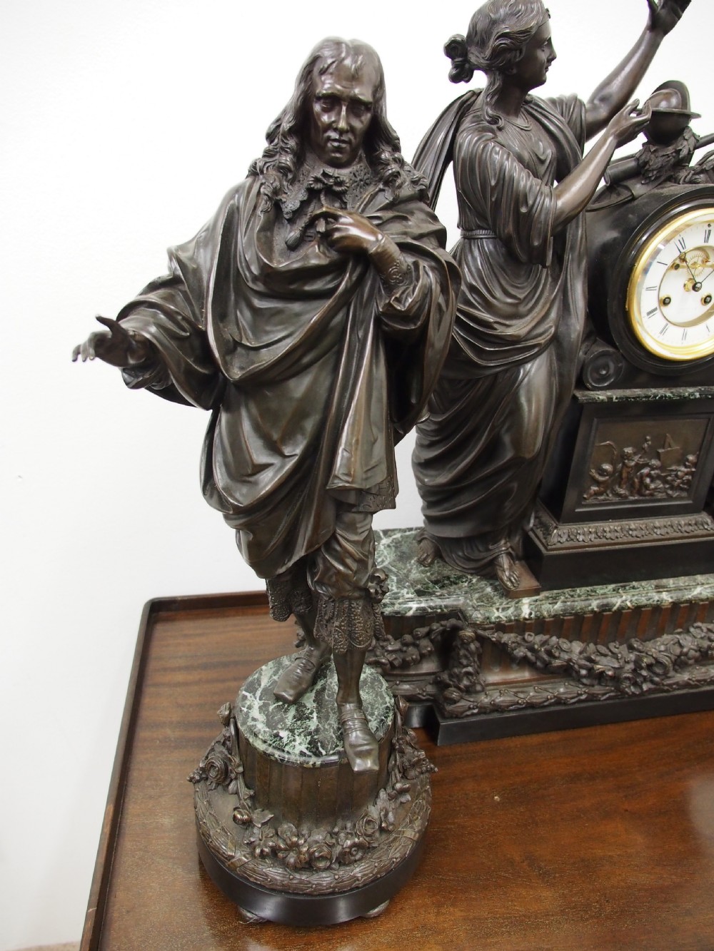 A three-piece French antique clock garniture featuring a central mantel clock flanked by classical female figures and two standalone bronze male sculptures on dark marble bases. View XIII