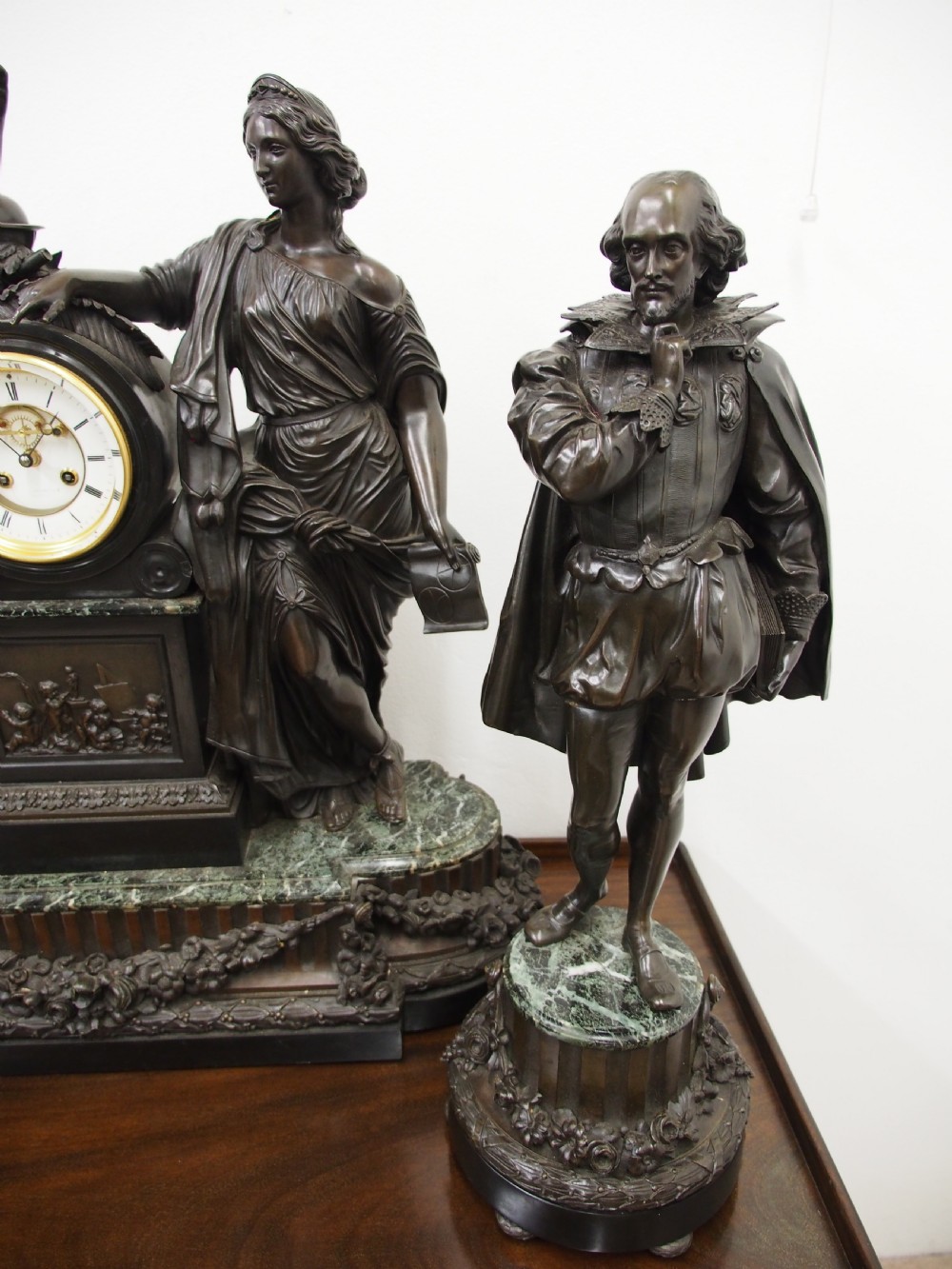 A three-piece French antique clock garniture featuring a central mantel clock flanked by classical female figures and two standalone bronze male sculptures on dark marble bases. View XIV