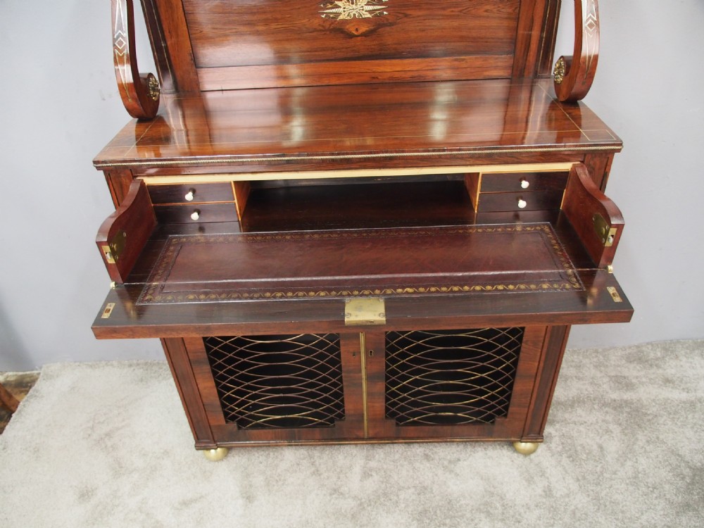 An antique Regency rosewood secretaire chiffonier featuring an upper tier shelf with S-scroll supports, brass mounts, and double doors with brass wire grilles. View VIII