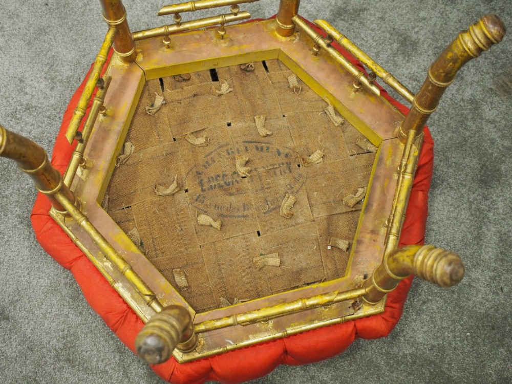 A circular footstool with deep-buttoned bright red silk upholstery set on carved giltwood legs designed to resemble bamboo. View II