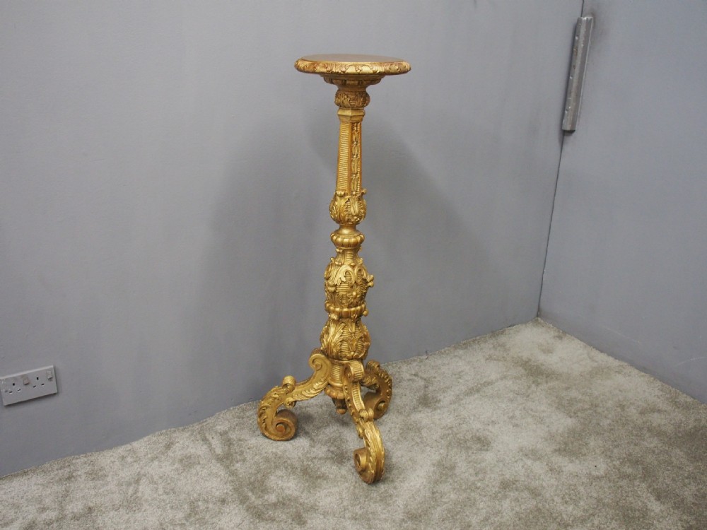 A tall Charles II style carved giltwood torchere stand with a circular top, baluster column decorated with foliage, and a tripod scroll base. View III