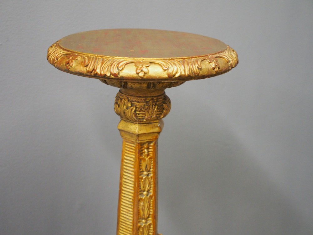 A tall Charles II style carved giltwood torchere stand with a circular top, baluster column decorated with foliage, and a tripod scroll base. View IV