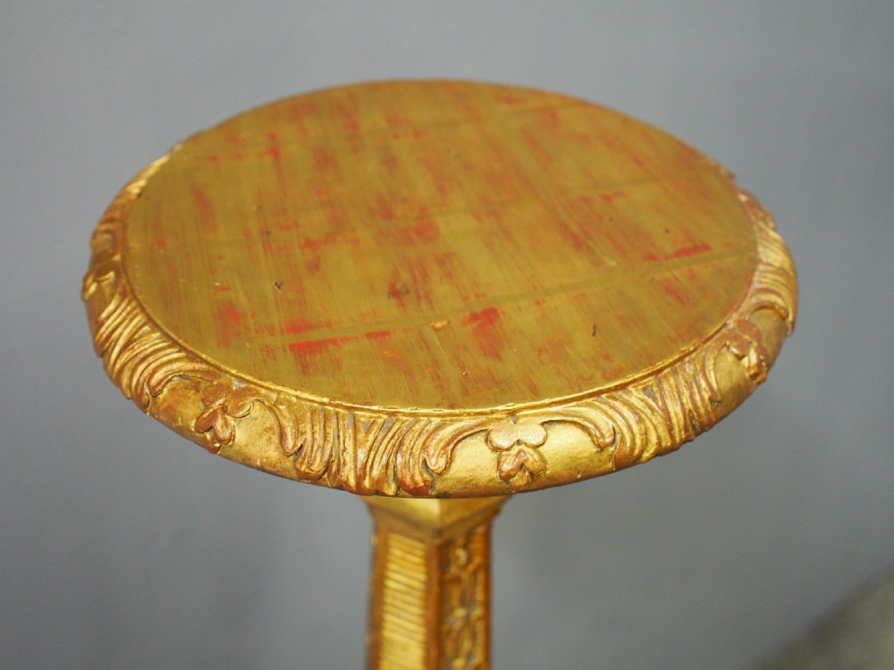 A tall Charles II style carved giltwood torchere stand with a circular top, baluster column decorated with foliage, and a tripod scroll base. View IX