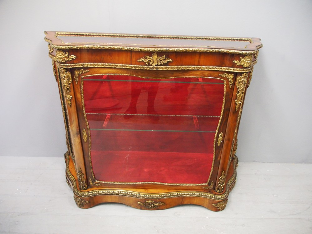 A Victorian yew wood vitrine display cabinet with gilt-bronze ormolu mounts, curved glass front, and red velvet lining. View XI