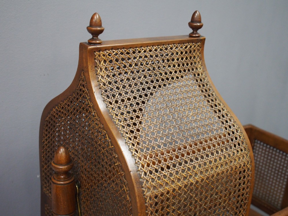 A William IV mahogany and cane cradle featuring a curved hooded canopy, turned side supports, and acorn finials. View IV