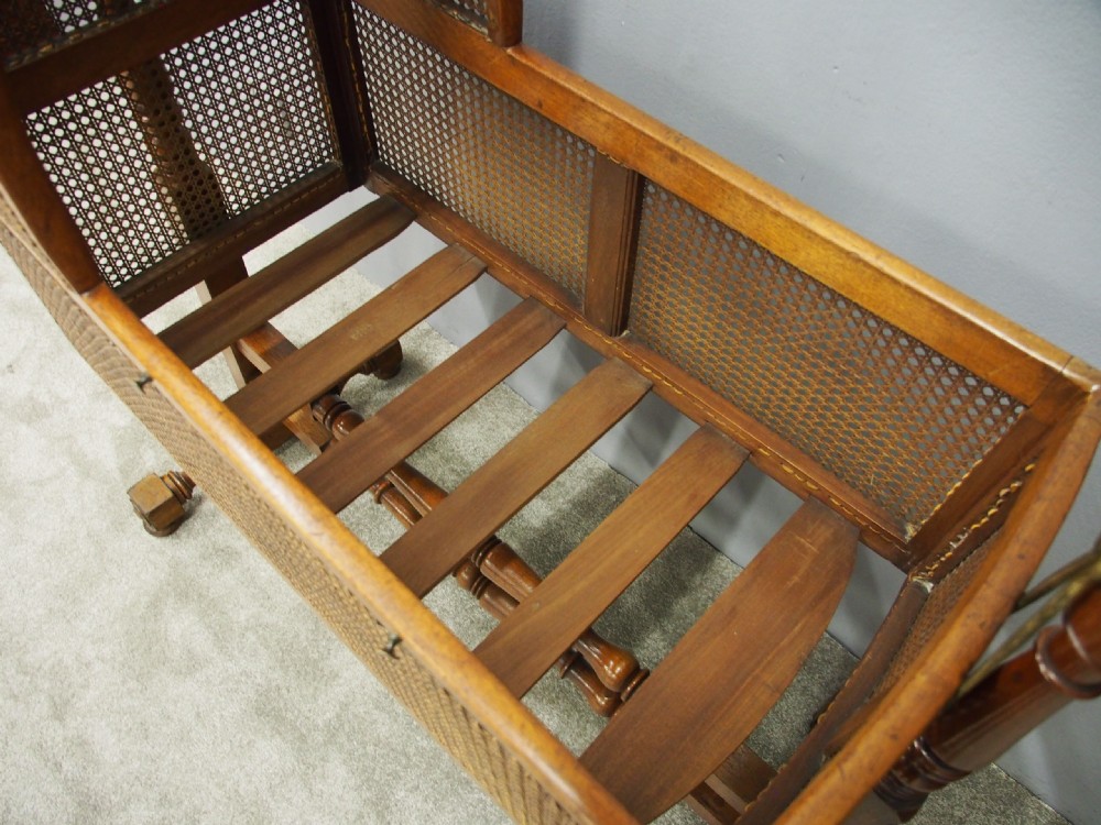A William IV mahogany and cane cradle featuring a curved hooded canopy, turned side supports, and acorn finials. View X