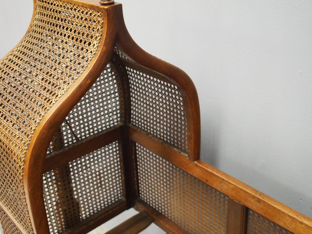 A William IV mahogany and cane cradle featuring a curved hooded canopy, turned side supports, and acorn finials. View XI