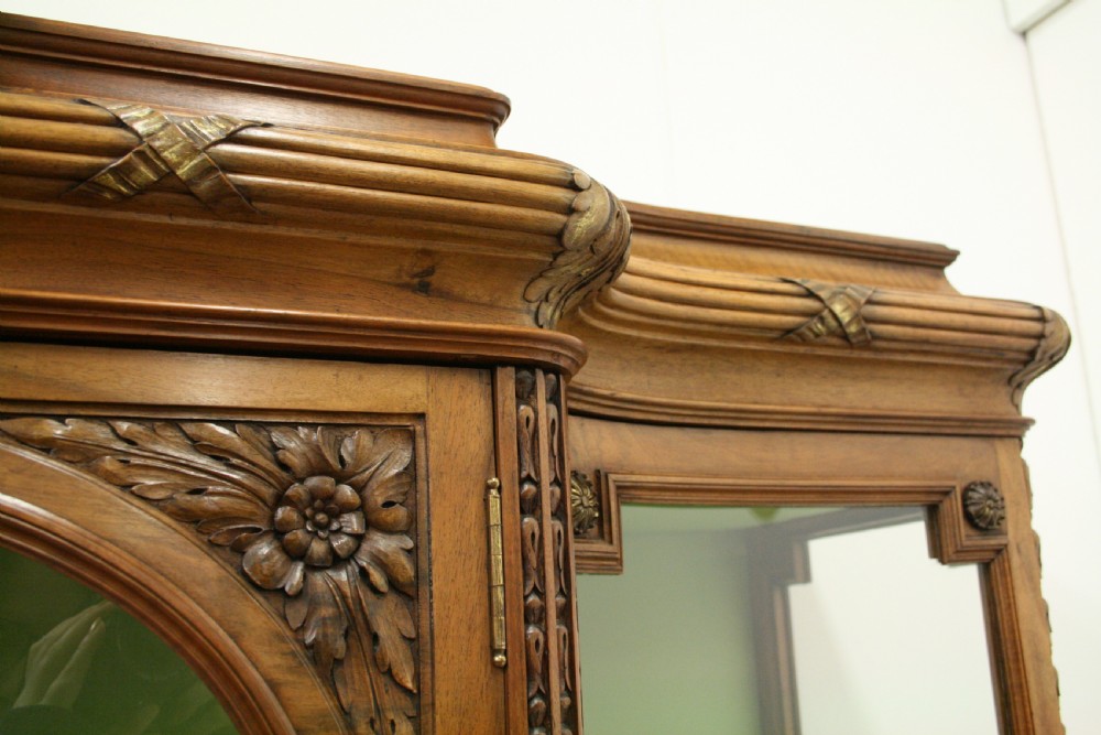 A carved walnut French display cabinet featuring glazed doors, glass shelves, green fabric interior lining, and turned fluted legs. View IV