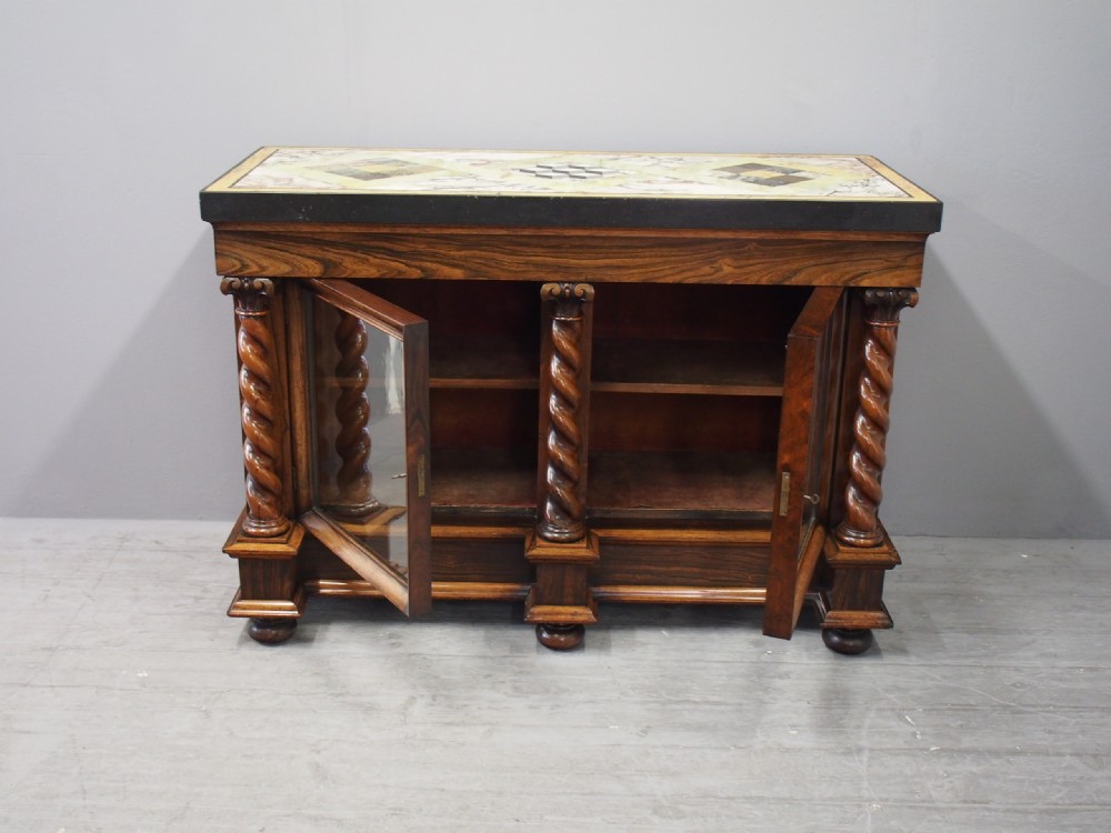A dark William IV rosewood side cabinet featuring a geometric specimen marble top, barley twist support columns, and two glass door panels. View XV