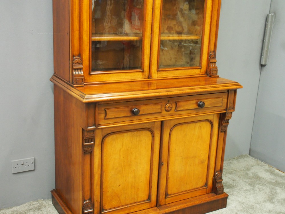 A mid-Victorian mahogany glazed bookcase cabinet with two glass upper doors above a two-door solid cupboard base with carved details. View III