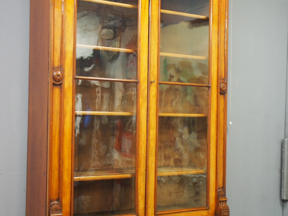 A mid-Victorian mahogany glazed bookcase cabinet with two glass upper doors above a two-door solid cupboard base with carved details. View V
